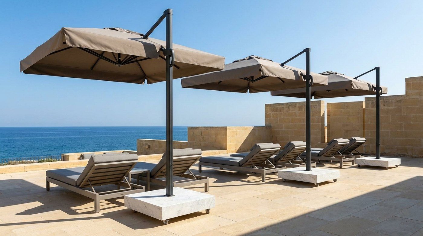 Square anthracite side-pole parasols over sun loungers beside a sea-view hotel pool on a limestone terrace