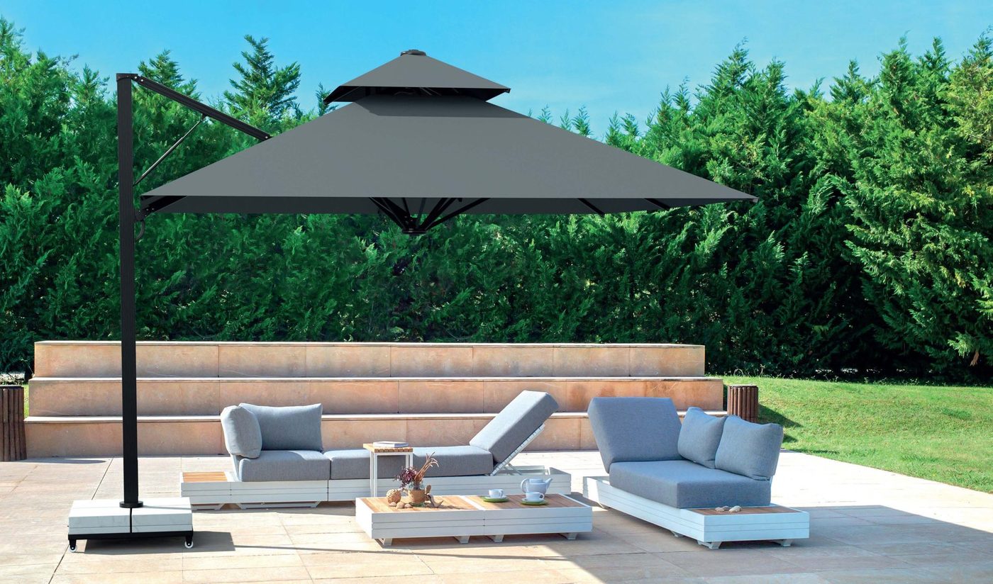 A square grey side-pole parasol with a vented top shading a white outdoor sofa set in a garden