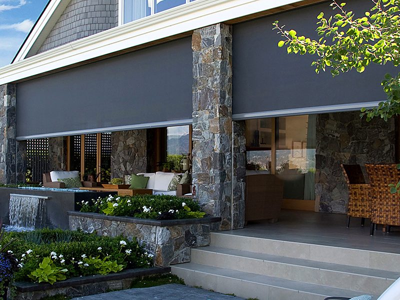 Dark zip screens lowered across the openings of a stone loggia