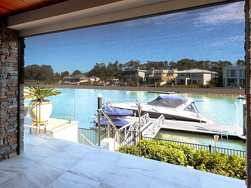 Looking out through a lowered mesh zip screen at boats moored on the water