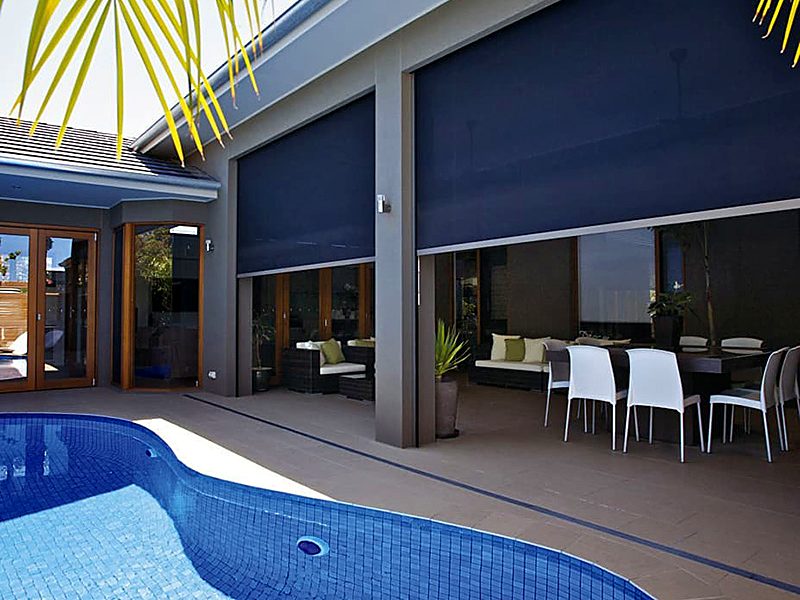 Grey zip screens lowered across a covered dining terrace beside a pool